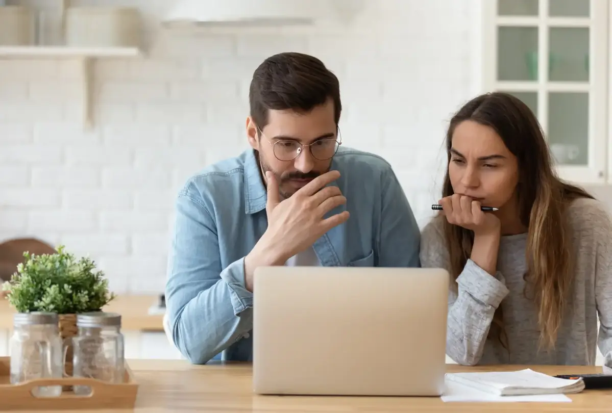 Eine Frau und ein Mann sitzen vor einem Laptop und schauen konzentriert auf den Bildschirm.