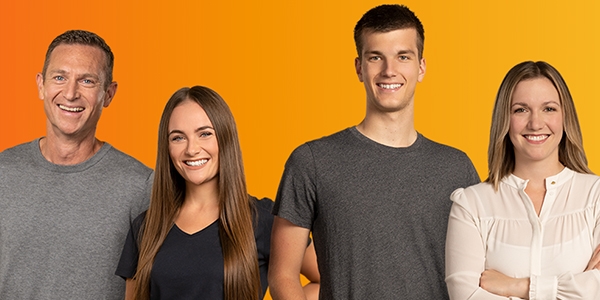 4 lächelnde evm-Mitarbeiter vor orangenem Hintergrund