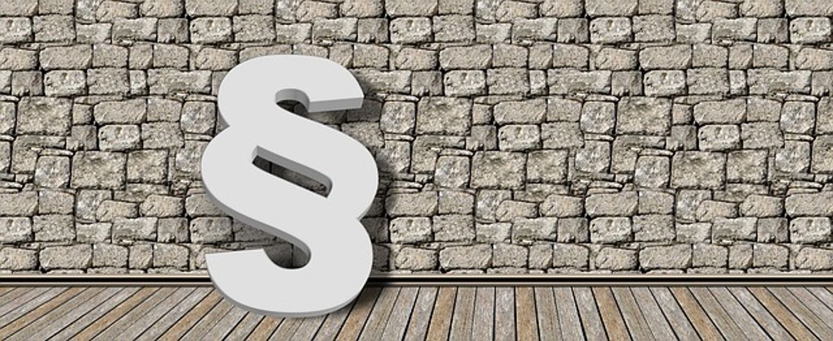 Ein großes Paragraphen-Zeichen, das an eine Steinwand gelehnt ist