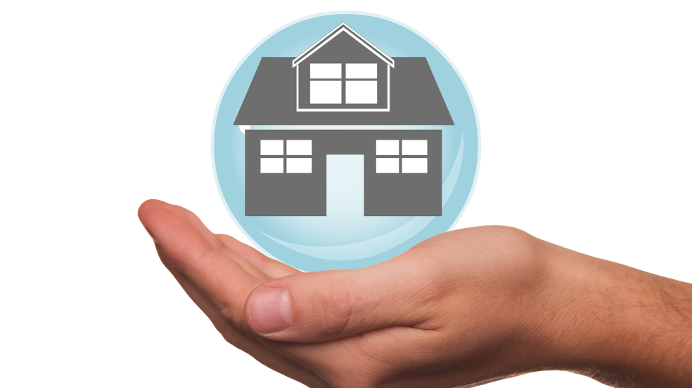 Eine Hand hält eine grafische Bubble in der Ein Haus eingezeichnet ist.