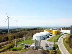 Himmelaufnahme auf ein Windrad neben einer Biogasanlage.