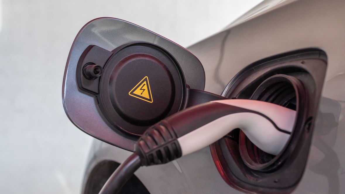 Ein E-Ladekabel lädt ein graues E-Auto.