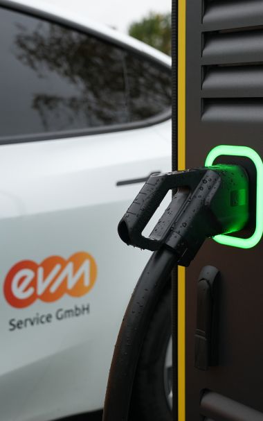 Neue Ladestationen in der Region Eine Ladestation im Close-Up. Im Hintergrund ist ein Auto der evm-Gruppe zu erkennen.