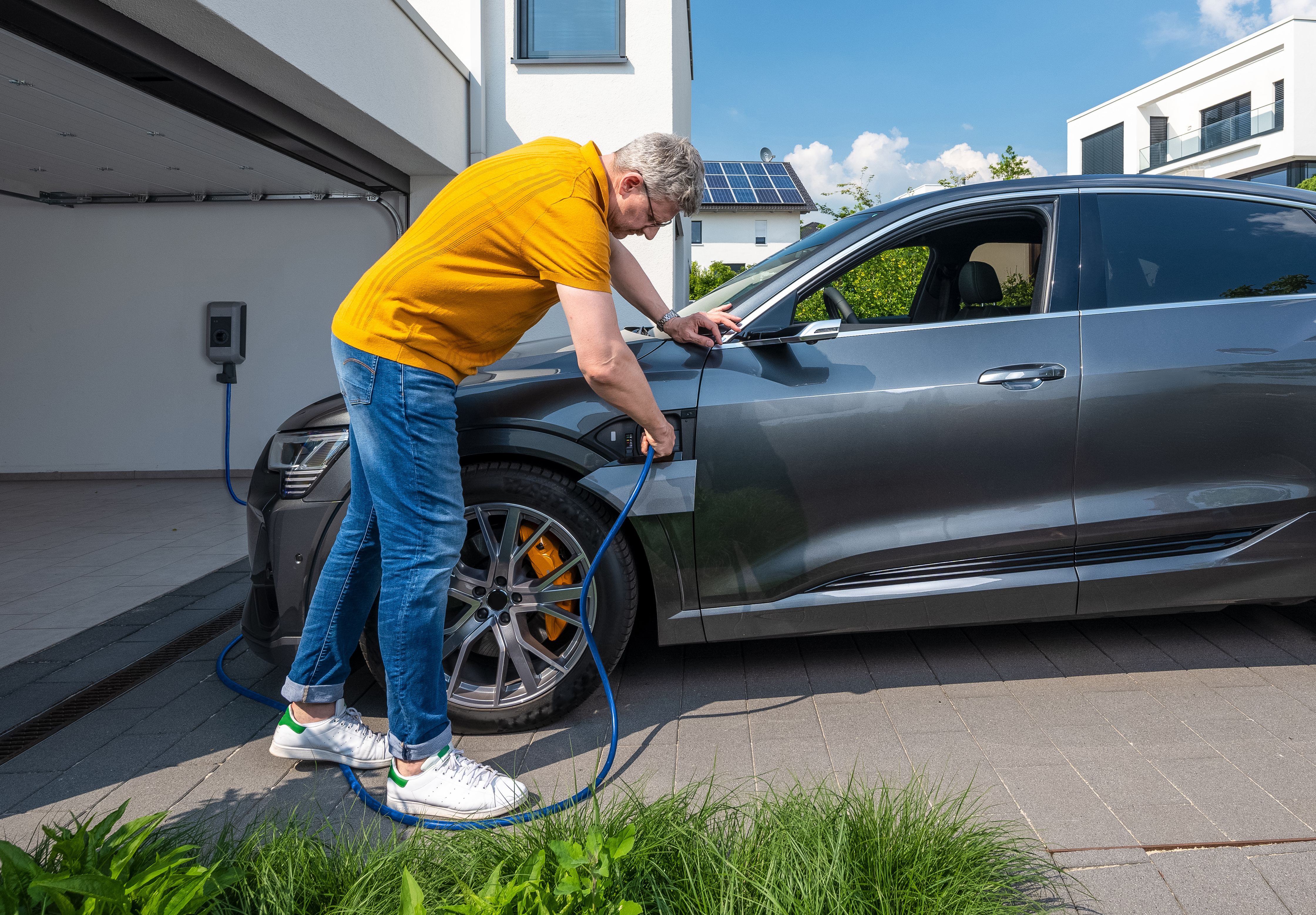 Ein Mann mit gelbem Poloshirt lädt sein E-Auto