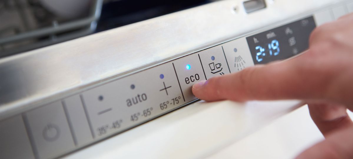 Eine nicht sichtbare Person zeigt auf den "eco" Schalter einer Waschmachine