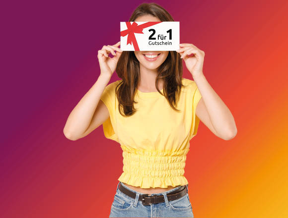 Eine Frau in einem gelben Oberteil hält einen Gutschein vor den Augen. Sie steht vor einem lila-orangenen Hintergrund.