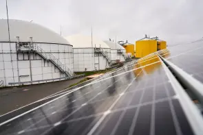 191206SDI1044 Im Vordergrund ist eine dunkle PV-Anlage zu erkennen. Links i Hintergrund befinden sich große weiße und gelbe Kessel.