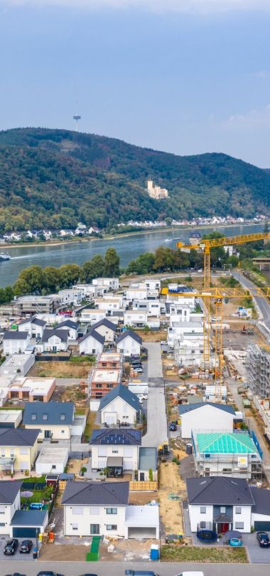 Himmelaufnahme auf ein Quartier mit mehreren Häusern und einer Baustelle eines mehrstöckigen Gebäudes.