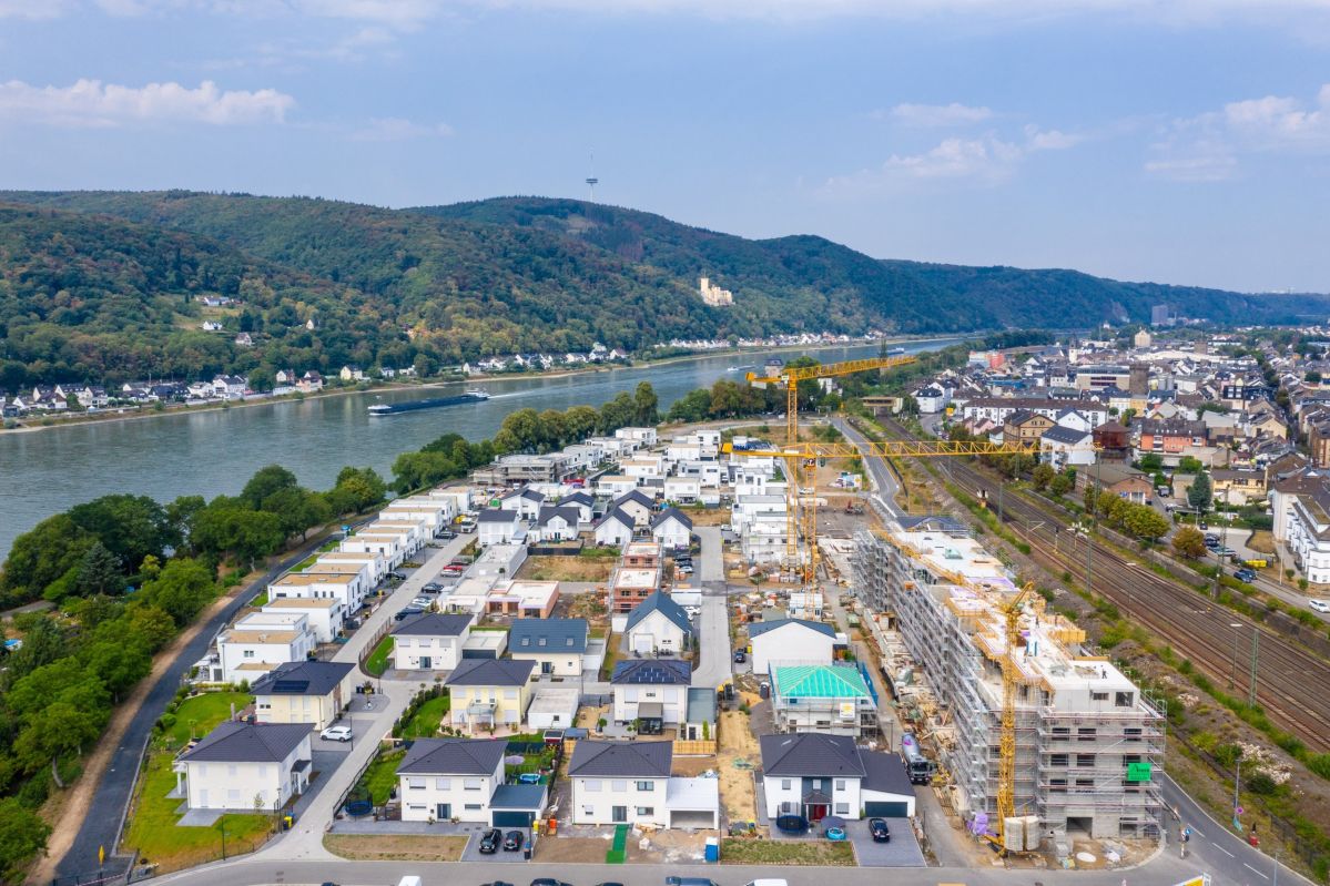 Himmelaufnahme auf ein Quartier mit mehreren Häusern und einer Baustelle eines mehrstöckigen Gebäudes.
