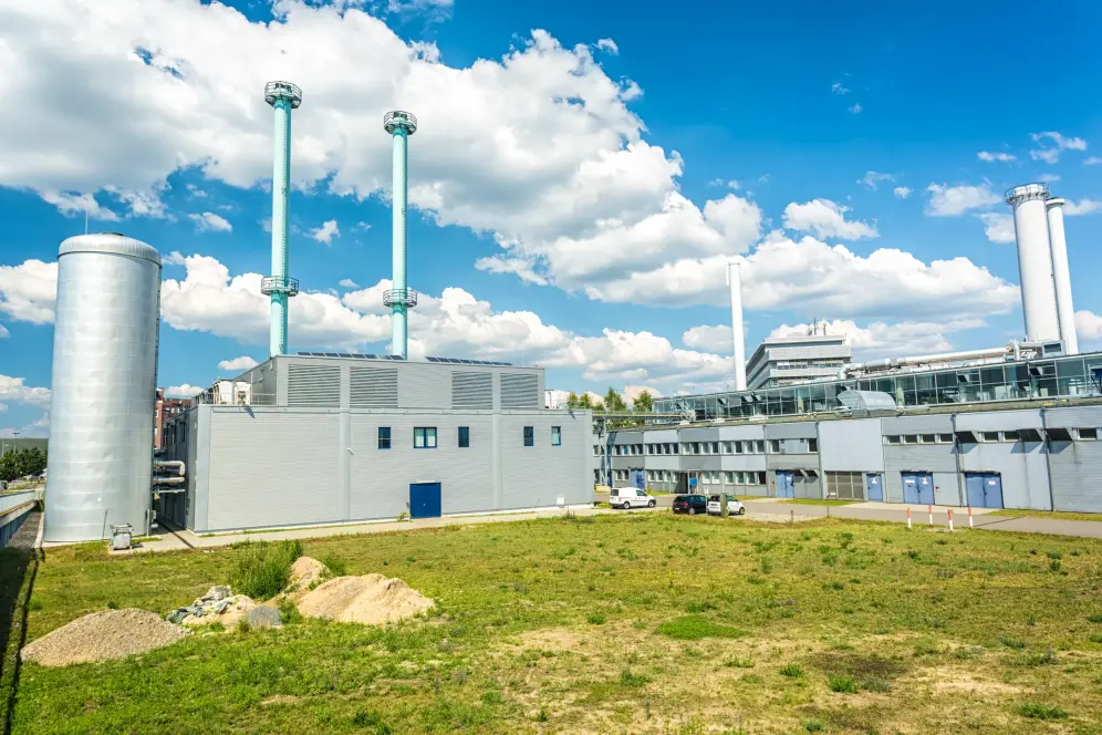 Cogeneration Plant Ein Blockheizkraftwerk mit einer grünen Wiese und einem blauen Himmel mit weißen Wolken.