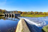 2216593721 Ninevija/Shutterstock Ein Wasserkraftwerk in einer grünen Umgebung mit einem blauen Himmel.