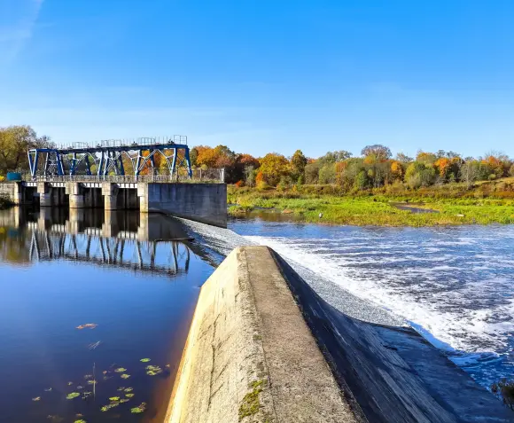 Ein Wasserkraftwerk in einer grünen Umgebung mit einem blauen Himmel.