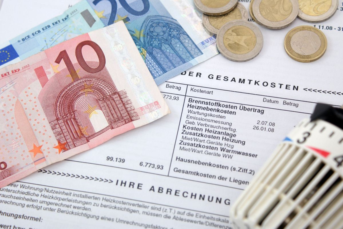 Geldscheine und Münzen über einer Heizungsrechnung