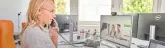 Eine Person telefoniert an einem Schreibtisch, während sie auf einen Monitor schaut, der eine evm-Webseite zeigt. Im Hintergrund befinden sich Fenster und Büroutensilien.