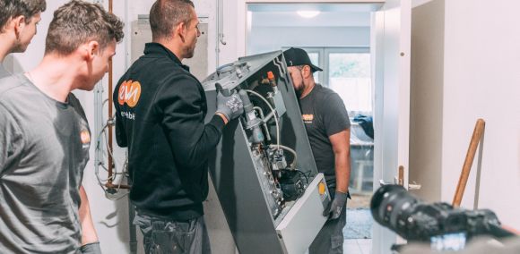 Einbau Wärmepumpe und PV Kunde Zwei Handwerker der evm tragen eine alte Heizung aus einem Keller