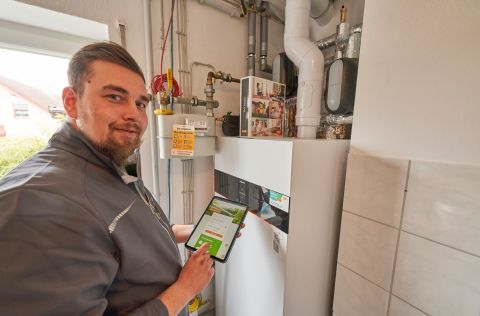 Ein Monteur der evms steht vor der neu eingebauten Heizungsanlage