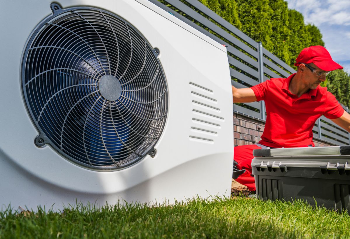 Wärmepumpen-Förderung bleibt – jetzt richtig planen Professional HVAC Worker in His 40s Installing Swimming Pool Heat Pump Outdoor Water Heating Device. Energy Saving Technologies.