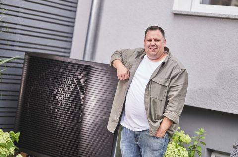 Markus Endlein ist rundum zufrieden mit seiner neuen Wärmepumpe Markus Endlein steht vor seiner neuen Wärmepumpe und lacht in die Kamera