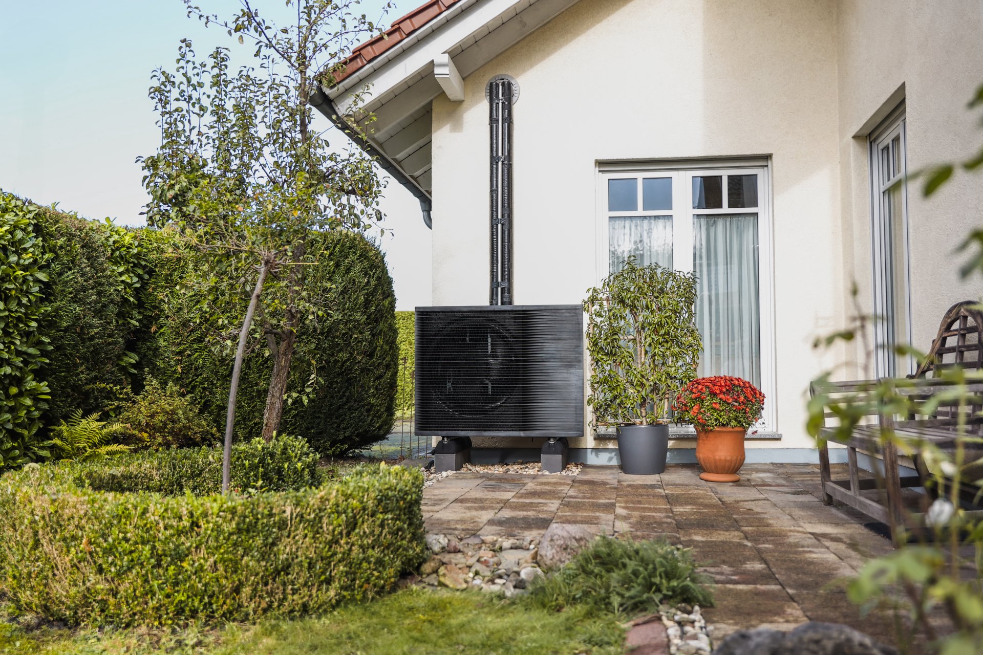 Das Außenelement einer Wärmepumpe vor einem Altbau.