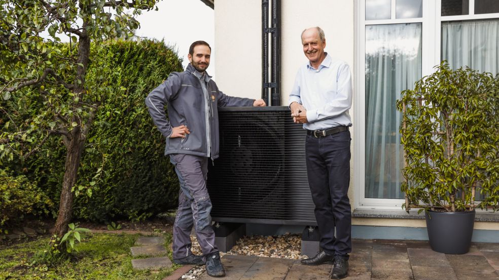 Sorgenfrei heizen im Ruhestand – Mit der Wärmepumpe von deiner evm in eine sichere Zukunft Herr Elsenberger und ein Berater der evms vor der Wärmepumpe