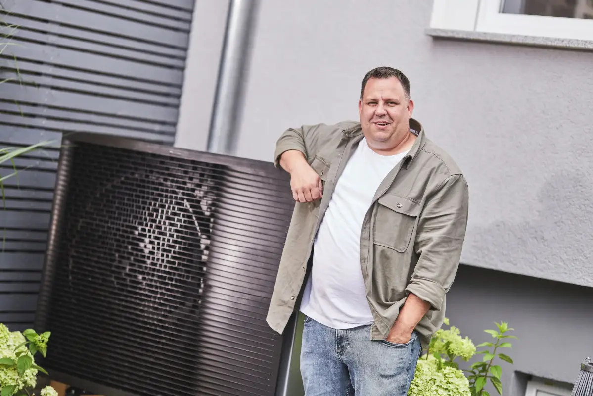 Wärmepumpe im Garten Mann steht an dem Außenelement einer Wärmepumpe