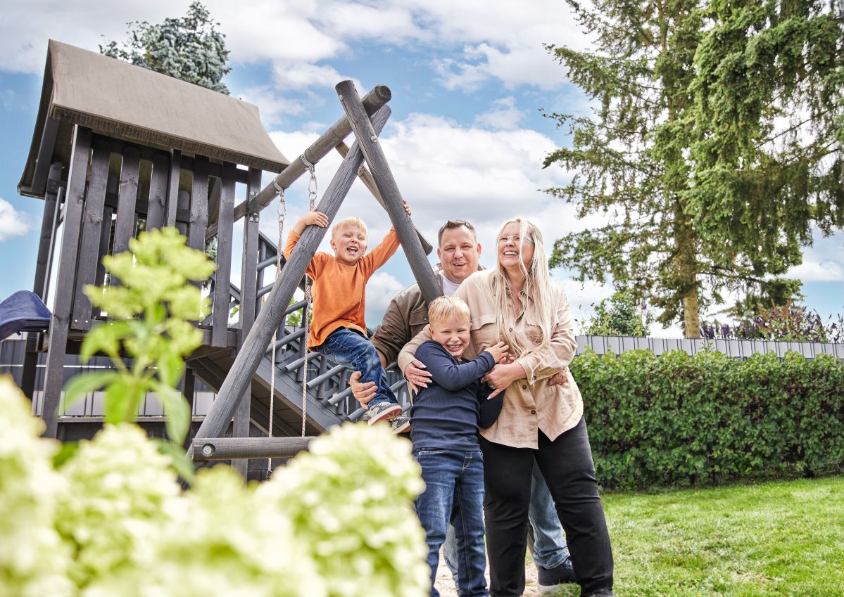 Eine Familie steht lachend in ihrem Garten