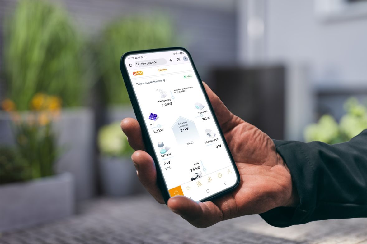 Eine Person hält ein Smartphone in der Hand und betrachtet in der evm⁺ App die aktuelle Energieübersicht mit Angaben zu Stromerzeugung, Verbrauch und Speicherstatus.