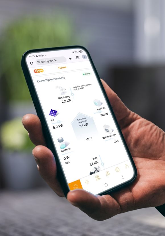 Eine Person hält ein Smartphone in der Hand und betrachtet in der evm⁺ App die aktuelle Energieübersicht mit Angaben zu Stromerzeugung, Verbrauch und Speicherstatus.