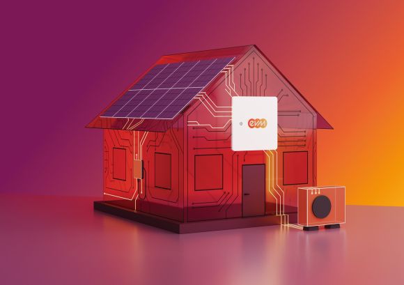 Ein stilisiertes Modellhaus mit Solarpanelen auf dem Dach steht auf einer glatten Fläche vor einem Farbverlauf aus Pink, Rot und Orange. Am Haus ist ein kleines Gerät mit dem evm‑Logo angebracht, daneben steht eine kompakte Wärmepumpeneinheit.