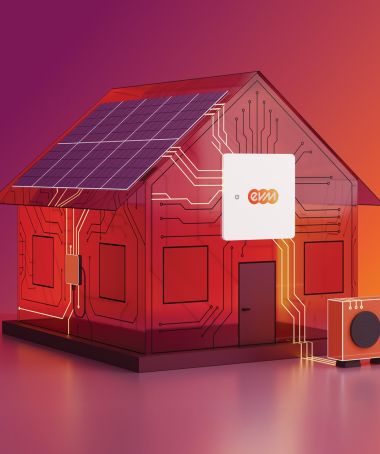 Ein stilisiertes Modellhaus mit Solarpanelen auf dem Dach steht auf einer glatten Fläche vor einem Farbverlauf aus Pink, Rot und Orange. Am Haus ist ein kleines Gerät mit dem evm‑Logo angebracht, daneben steht eine kompakte Wärmepumpeneinheit.