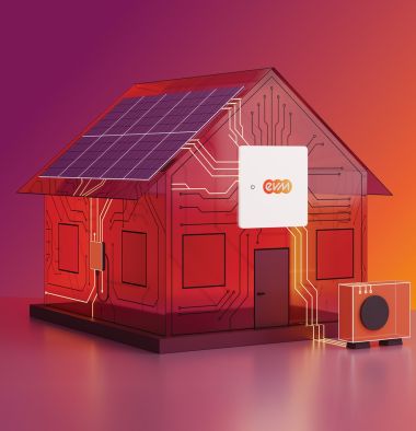 Ein stilisiertes Modellhaus mit Solarpanelen auf dem Dach steht auf einer glatten Fläche vor einem Farbverlauf aus Pink, Rot und Orange. Am Haus ist ein kleines Gerät mit dem evm‑Logo angebracht, daneben steht eine kompakte Wärmepumpeneinheit.