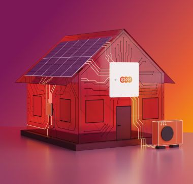 Ein stilisiertes Modellhaus mit Solarpanelen auf dem Dach steht auf einer glatten Fläche vor einem Farbverlauf aus Pink, Rot und Orange. Am Haus ist ein kleines Gerät mit dem evm‑Logo angebracht, daneben steht eine kompakte Wärmepumpeneinheit.