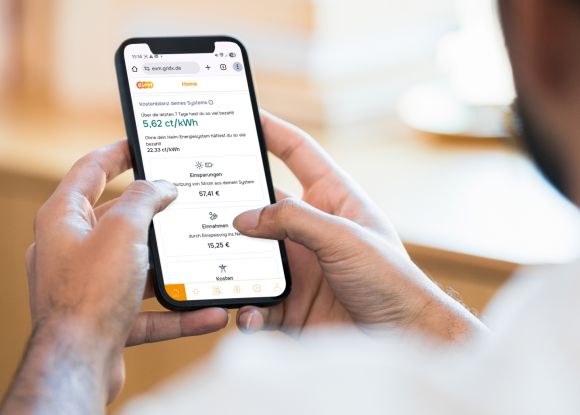Mann hält Handy in der Hand und schaut sich die evm+ Energiepilot App an
