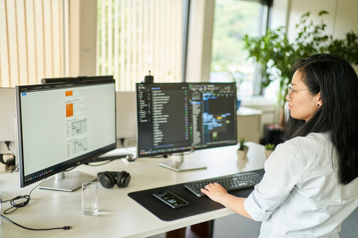 IT Kollegin sitzt am Schreibtisch mit zwei Bildschirmen und löst die Anliegen der Kolleginnen und Kollegen, die durch das IT-Servicemanagement gemeldet wurden. 