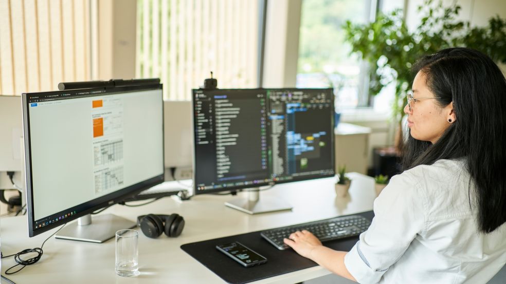 IT Kollegin sitzt am Schreibtisch mit zwei Bildschirmen und löst die Anliegen der Kolleginnen und Kollegen, die durch das IT-Servicemanagement gemeldet wurden. 