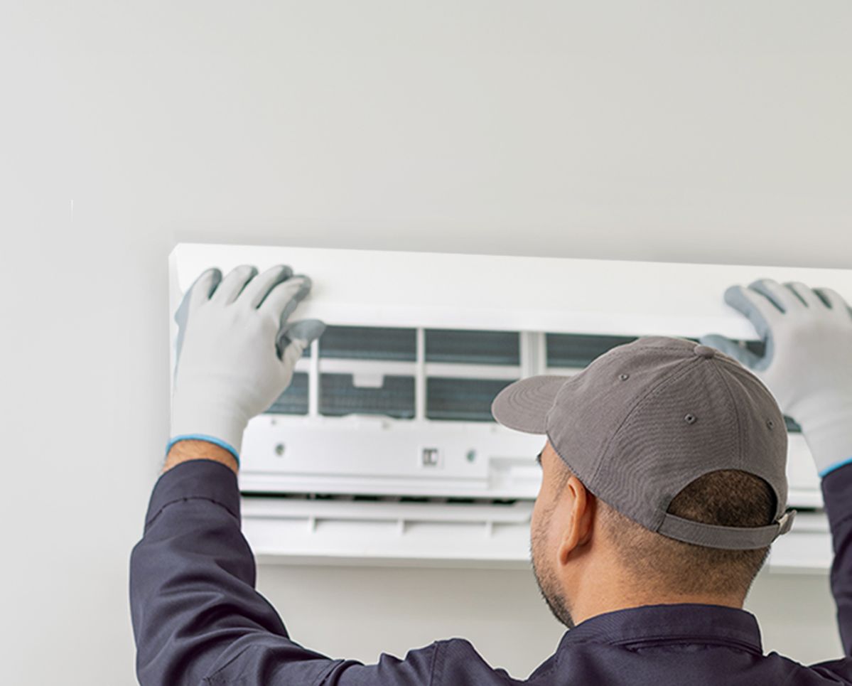 Ein Mann mit einer grauen evm Service GmbH Jacke mit orangenem evm Logo arbeitet an einer Klimaanlage.