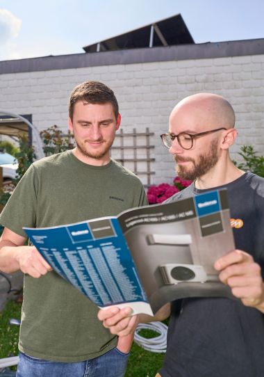 evm-Service -Begleitung beim Einbau einer Klimaanlage Zwei Männer stehen im Garten und lesen eine Broschüre über Klimaanlagen