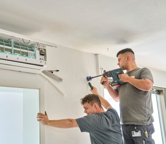 Zwei evm Mitarbeiter bauen eine Klimaanlage ein