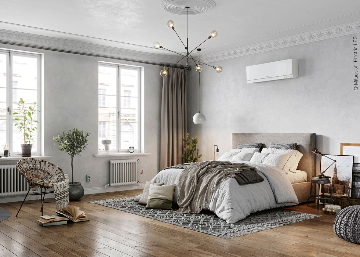 Ein modern eingerichtetes Schlafzimmer mit einem freistehendem Bett. Über dem Bett befindet sich eine weiße Klimaanlage.