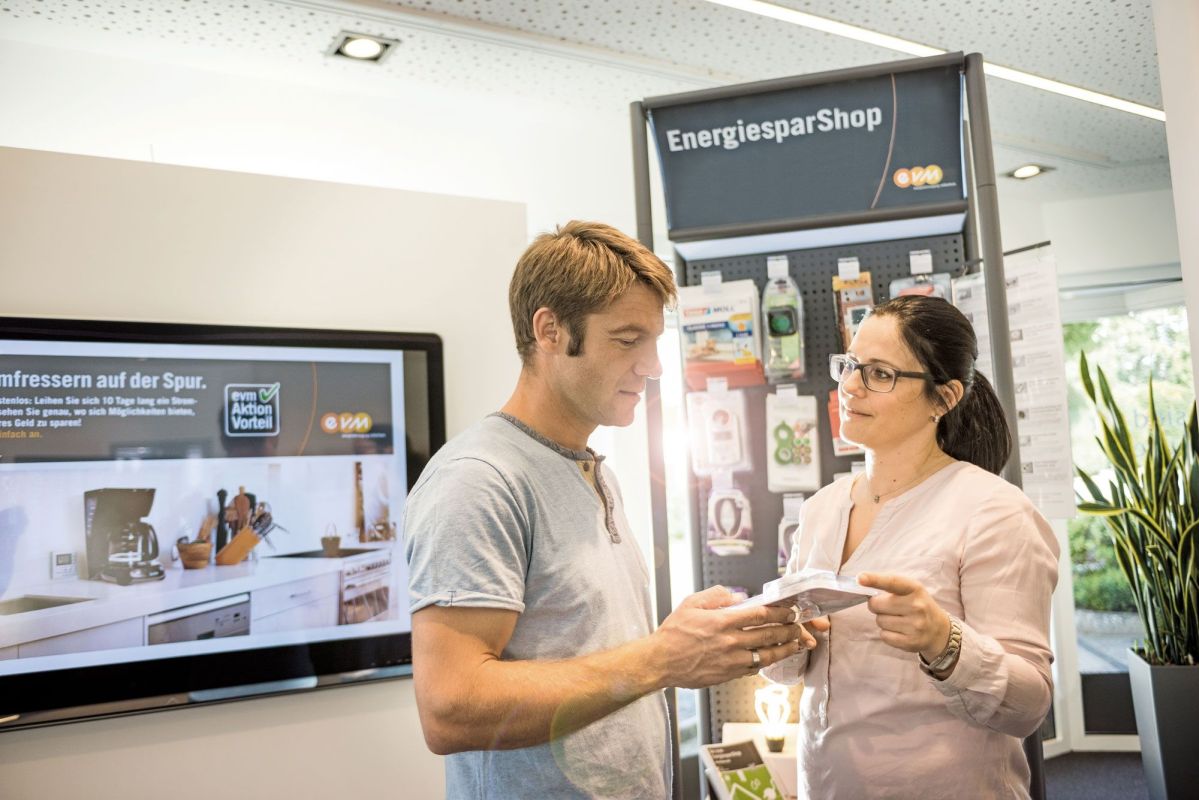 Eine Frau und ein Mann stehen in einem evm Kundenzentrum und schauen auf einen Flyer.