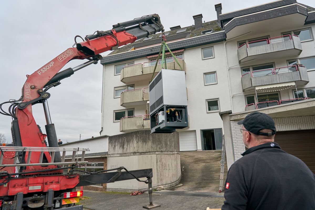 Mit Präzision hebt der Kranführer die neue Wärmepumpe auf ihr Fundament. Sie heizt in Kürze die insgesamt 14 Wohneinheiten des Mehrfamilienhauses in der Südlichen Vorstadt. Das Außenelement einer Wärmepumpe an einem Kran