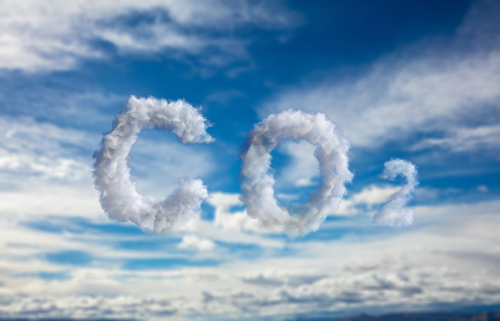 CO₂-Kohlendioxid-Verschmutzungszeichen. Emissions-Smogwolken-Symbol vor einem blauen, bewölkten Himmel. Konzept für Klimawandel und globale Erwärmung.