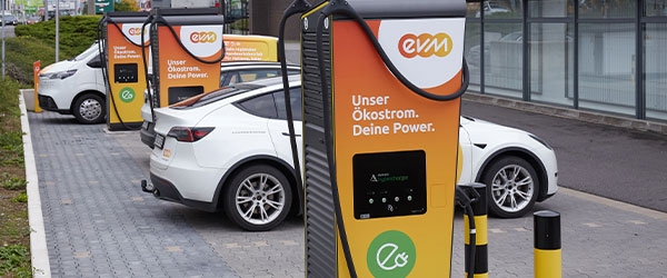 Drei Lades&auml;ulen der evm in Orange und Schwarz an denen zwei Autos laden