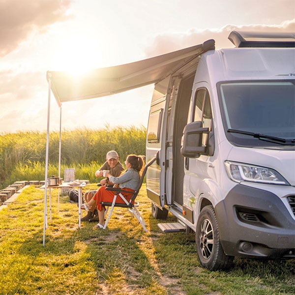 Paar campt mit einem Wohnwagen an einem sonnigen Tag