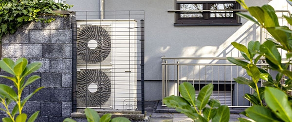 Das Au&szlig;enelement einer W&auml;rmepumpe umringt von Pflanzen