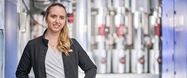 Lächelnde Projektleiterin Nadine Kuhlmann vor technischen Anlagen.