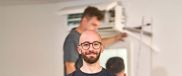 Hauke Fuchs im Vordergrund, im Hintergrund wird eine Klimaanlage installiert