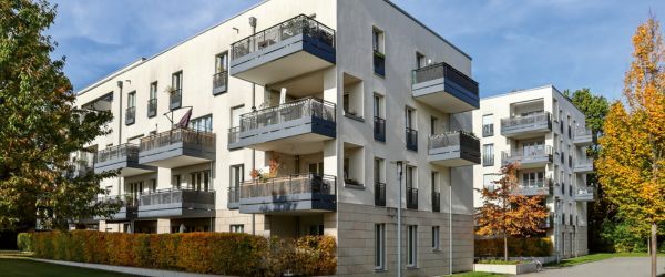 Au&szlig;enansicht eines wei&szlig;en, modernen Mehrfamilienhauses mit Balkonen