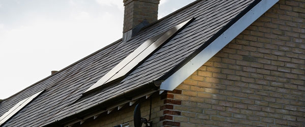 Ein Hausdach mit Schieferplatten und Solarpanelen