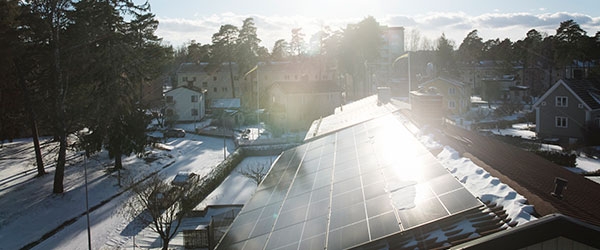 Wintersonne scheint auf eine PV-Anlage auf einem verschneiten Dach